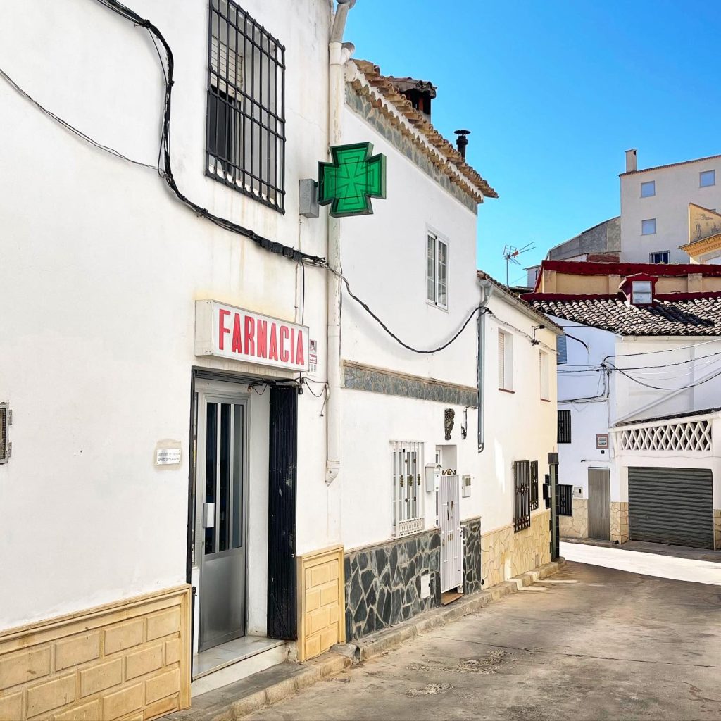 Fachada de la farmacia en una calle tranquila.